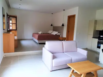 a living room with a white couch and a bed at Galini View Apartments Lindos in Líndos