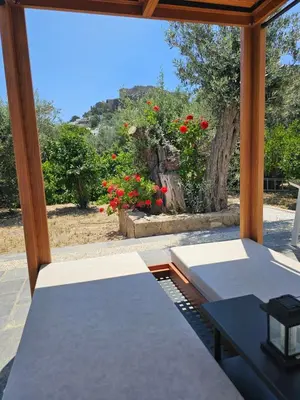a porch with a bed and a window with red flowers at Galini View Apartments Lindos in Líndos