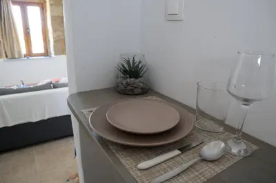 a table with a plate and wine glasses on it at Heliophilia Lindos in Líndos