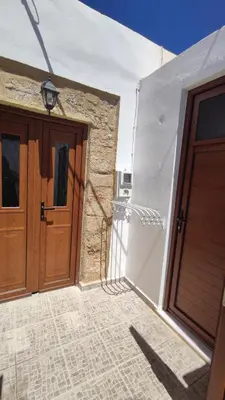 a pair of wooden doors on a white building at Heliophilia Lindos in Líndos