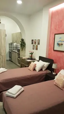 a room with two beds and a kitchen in the background at Lolos' house in Rhodes Town