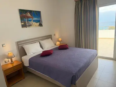 a bedroom with a bed with two red pillows at Red Hibiscus Stegna in Archangelos