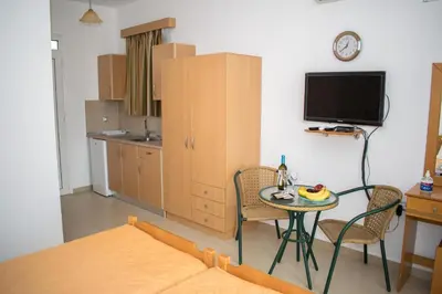 a living room with a table and chairs and a kitchen at Red Hibiscus Stegna in Archangelos