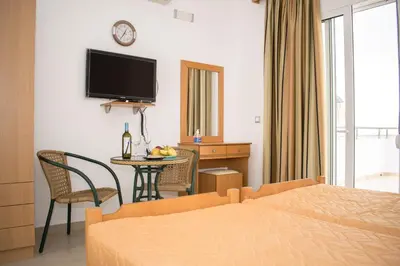 a hotel room with a bed and a table and a television at Red Hibiscus Stegna in Archangelos