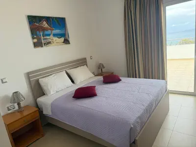 a bedroom with a bed with a view of the ocean at Red Hibiscus Stegna in Archangelos
