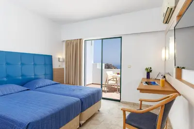 a bedroom with a blue bed and a balcony at LINDOS GARDENS RESORT COMPLEX in Líndos