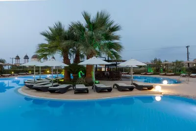 a swimming pool with lounge chairs and umbrellas at LINDOS GARDENS RESORT COMPLEX in Líndos