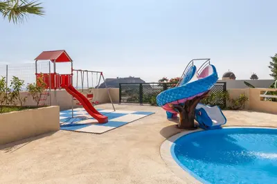 a pool with a slide and a playground at LINDOS GARDENS RESORT COMPLEX in Líndos
