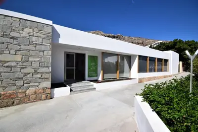 a white building with a stone wall at LINDOS GARDENS RESORT COMPLEX in Líndos