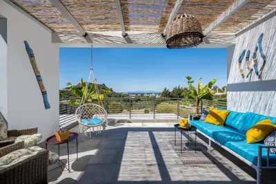 a patio with a blue couch and a swing at Wonderview Exclusive Apartment in Kremasti