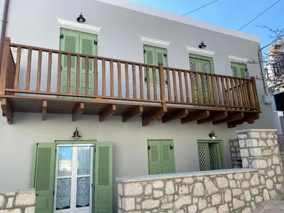 a house with a staircase and green shutters at LUCA'S HOUSES in Halki