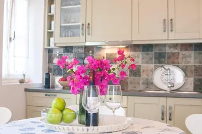 a kitchen with a table with a vase with pink flowers at LUCA'S HOUSES in Halki