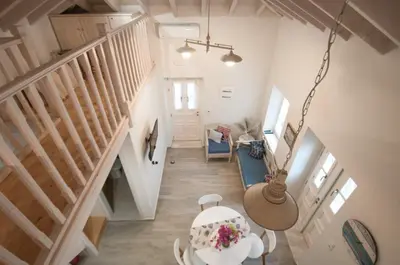 a living room with a staircase and a table and a room at LUCA'S HOUSES in Halki