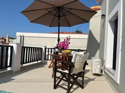 a wooden table with an umbrella on a balcony at LUCA'S HOUSES in Halki