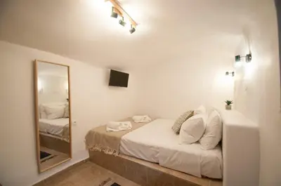 a white bedroom with a mirror and a bed at LUCA'S HOUSES in Halki