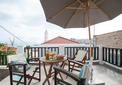 a table and chairs on a balcony with an umbrella at LUCA'S HOUSES in Halki