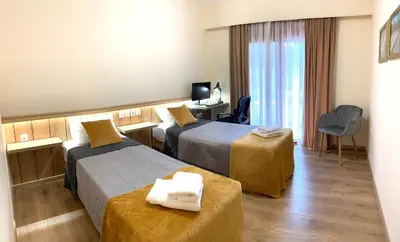 a hotel room with two beds and a desk at A&B Rhodes city apartments in Rhodes Town