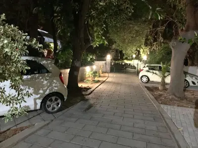 two cars parked on the side of a sidewalk at night at A&B Rhodes city apartments in Rhodes Town