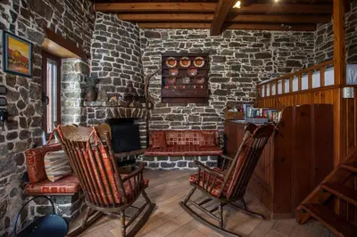 a living room with two rocking chairs and a stone fireplace at Echo Traditional House - Ηχώ Παραδοσιακό Σπίτι in Émbonas