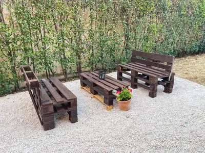 two wooden benches and a potted plant next to a wall at Echo Traditional House - Ηχώ Παραδοσιακό Σπίτι in Émbonas