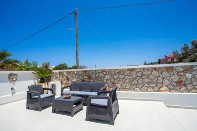 a patio with chairs and a table and a stone wall at Pegasus Villa in Ialyssos