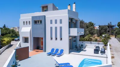 a white house with chairs and a swimming pool at Pegasus Villa in Ialyssos