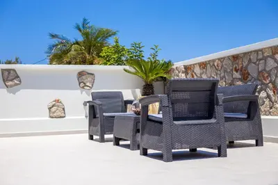 a group of wicker chairs and a table on a patio at Pegasus Villa in Ialyssos