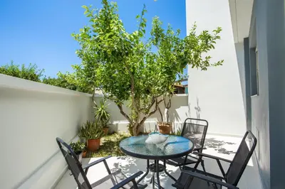 a patio with a table and chairs and a tree at Pegasus Villa in Ialyssos