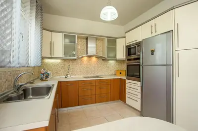 a kitchen with wooden cabinets and a stainless steel refrigerator at Pegasus Villa in Ialyssos