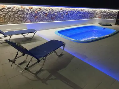 a swimming pool with a chair and a table in front of it at Pegasus Villa in Ialyssos