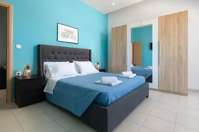 a bedroom with a large bed with blue walls at Rhodes Sea Ialysos Apartment in Ialyssos