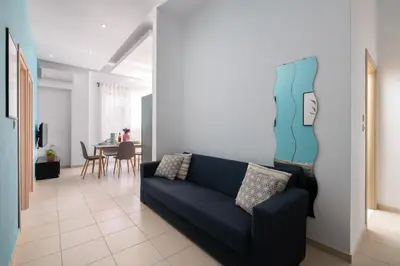 a living room with a blue couch and a table at Rhodes Sea Ialysos Apartment in Ialyssos