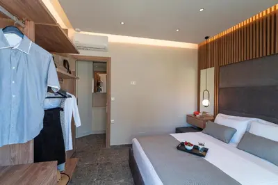 a hotel room with a bed and a shirt on a rack at Palmeral Luxury Suites in Rhodes Town