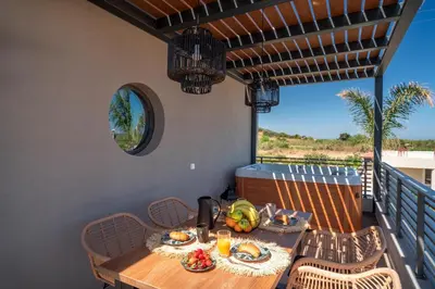 a table and chairs on a balcony with a meal on it at Palmeral Luxury Suites in Rhodes Town