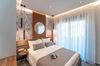 a bedroom with a large bed and a mirror at Palmeral Luxury Suites in Rhodes Town