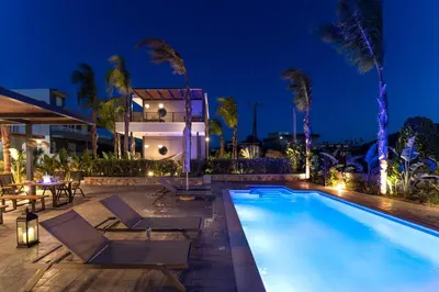 a villa with a swimming pool at night at Palmeral Luxury Suites in Rhodes Town