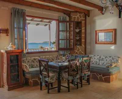 a living room with a couch and a table and chairs at Villa Limnioni in Archangelos