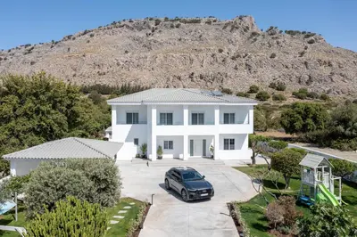 a white house with a car parked in the driveway at M Mansion in Pefki Rhodes