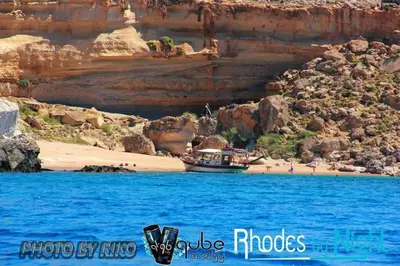 a boat on a beach next to a beach at stegna on sea apt in Archangelos