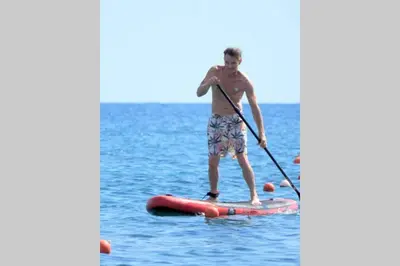 a man standing on a paddle board in the water at stegna on sea apt in Archangelos