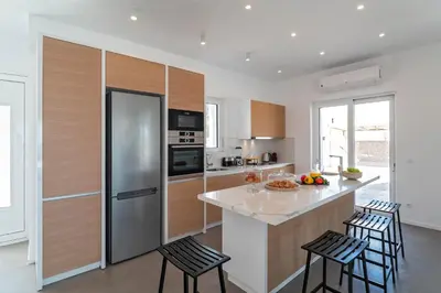 a kitchen with a stainless steel refrigerator and two bar stools at Nora Villa in Afantou