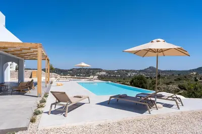 a villa with a swimming pool with chairs and an umbrella at Nora Villa in Afantou