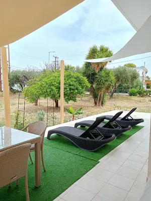a patio with a table and chairs on a green rug at Spacious Beach House Theologos in Theologos