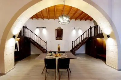 a dining room with a table and a staircase at Paraskevi Luxury Apartments in Kattavía