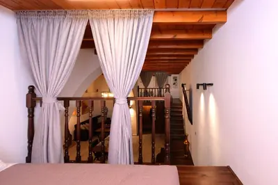 a bedroom with white curtains and a staircase at Paraskevi Luxury Apartments in Kattavía