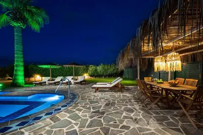 a patio with a table and a pool at night at Villa Palmeras in Soroni
