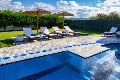 a group of chairs and umbrellas next to a pool at Villa Palmeras in Soroni