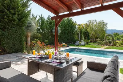 a patio with a table and chairs next to a swimming pool at Zenia Villa in Paradeísion