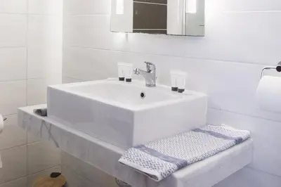 a white bathroom with a sink and a mirror at Ladiko Inn Hotel Faliraki -Anthony Quinn Bay in Faliraki