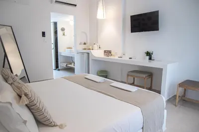 a white bedroom with a large bed and a bathroom at Ladiko Inn Hotel Faliraki -Anthony Quinn Bay in Faliraki